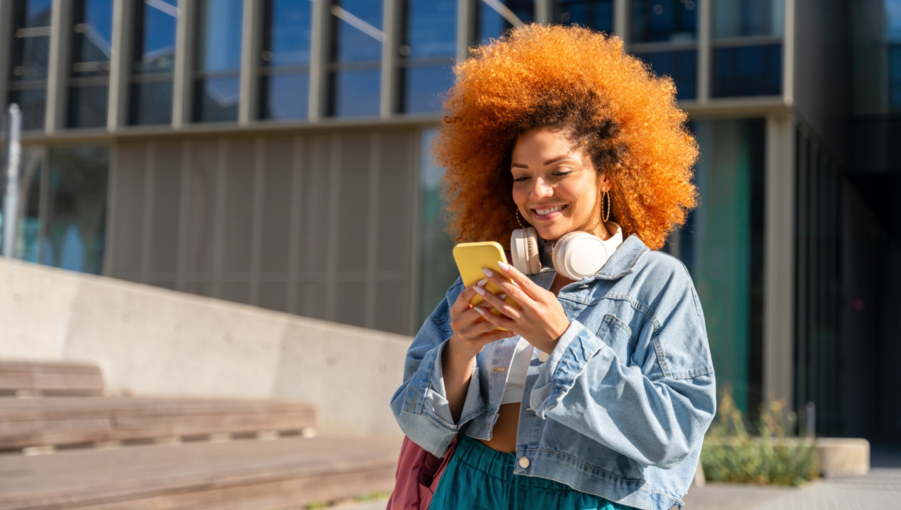 Mulher jovem a andar na rua a mexer no telemóvel